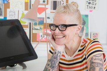 Lisa Congdon sits at her desk in her studio, smiling at the camera.