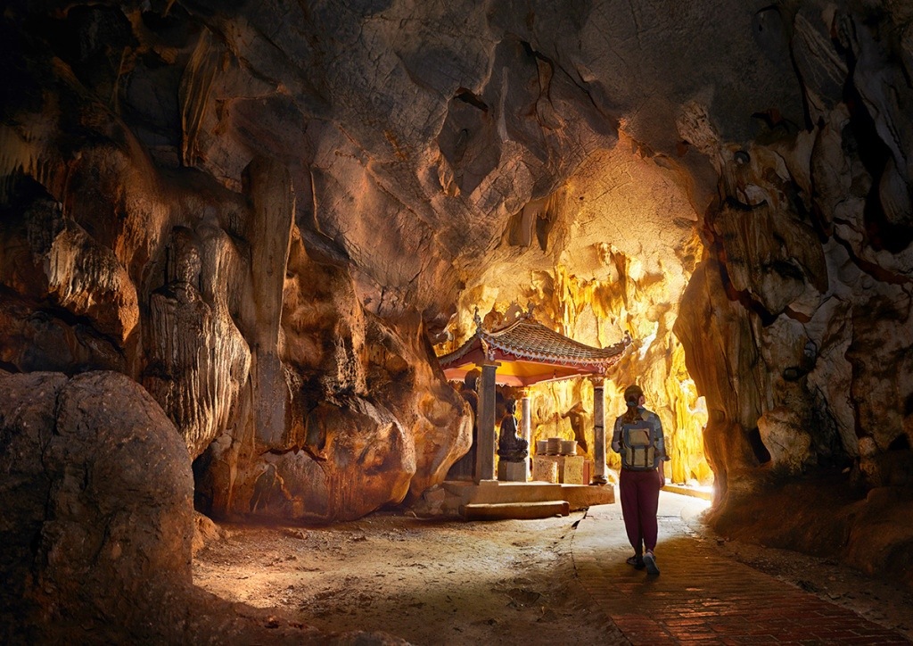 A hiker explores the fusion of cave and pagoda at Bich Dong.
