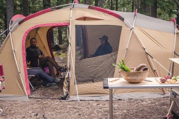Glamping site with camping couch, camping kitchen and large tan tent.
