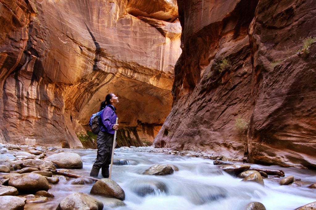 A hiker plods through The Narrows in Zion National Park.