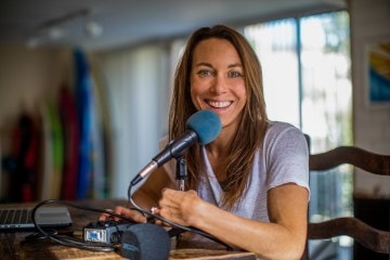Shelby sitting behind a microphone, smiling at the camera.
