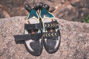 A pair of climbing shoes rest on a rock.