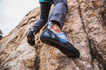 A climber uses their feet to move up an outdoor rock face.