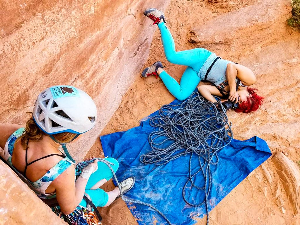 A photographer lies on the ground to get an interesting angle, shooting a photo of a climber.