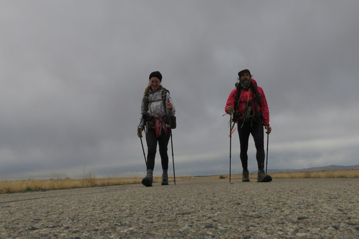 Two thru-hikers walk toward the camera on an abandoned road.