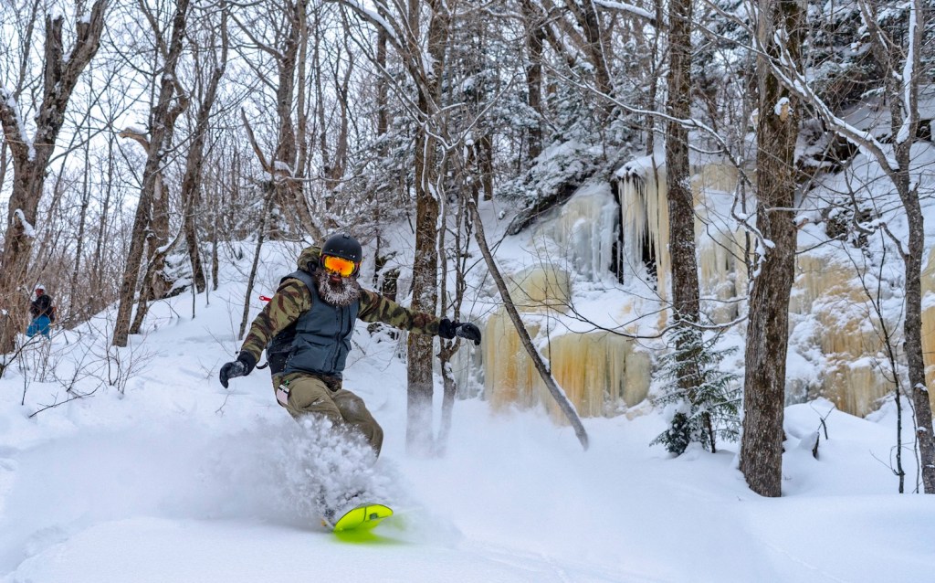 A backcountry snowboarder finds powder out the gates at Vermont's Bolton Valley ski area.