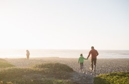 A family gazes into the mist on a beach