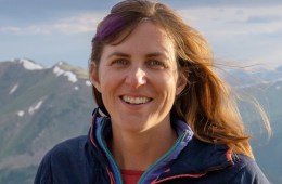 Meg's head and shoulders in front of a beautiful mountain range.