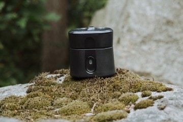 Thermacell Radius resting on moss on a gray rock.