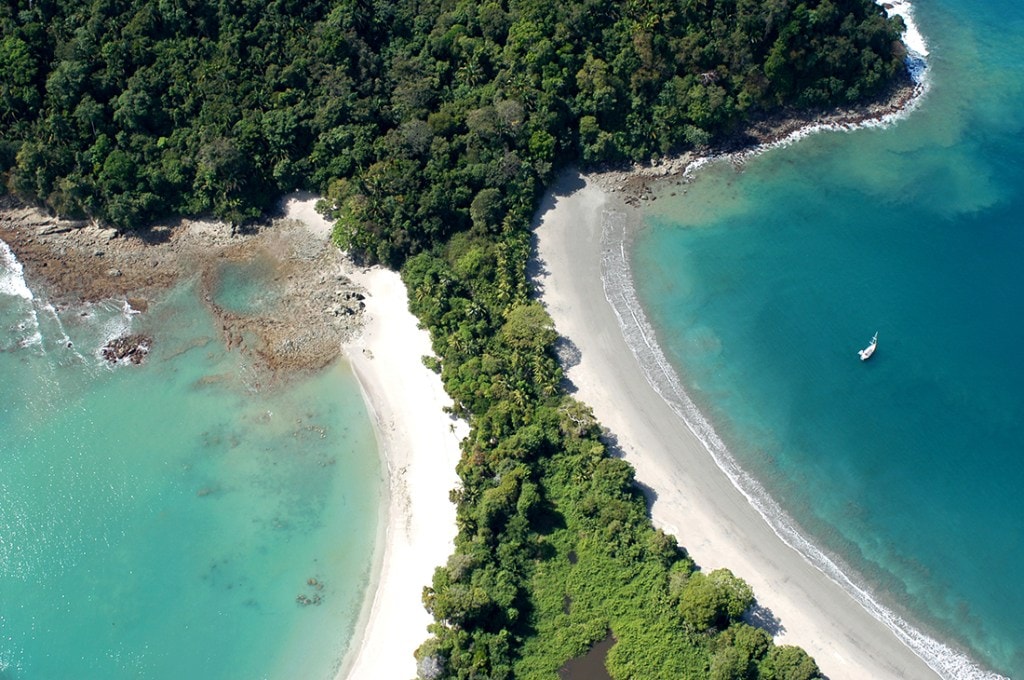 A narrow strip of jungle-clad land pierces tropical-blue waters. 
