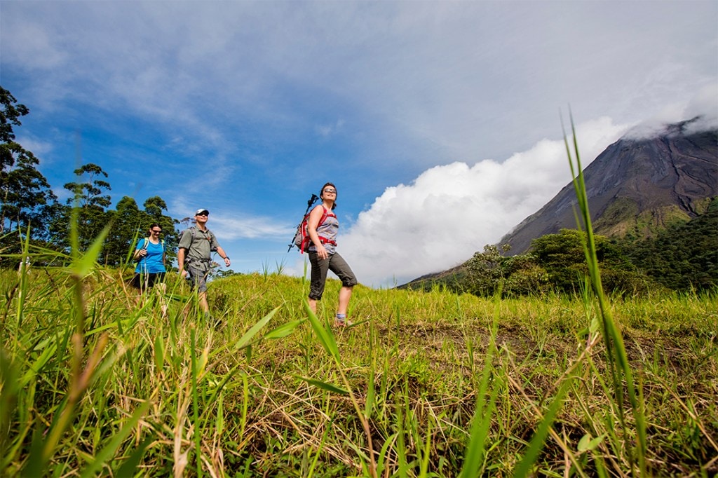 Hikers on an REI Adventures tour enjoy the grand aesthetic of Arenal Volcano National Park.