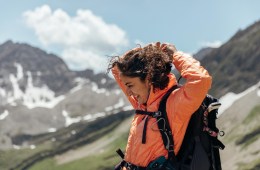 A hiker adjusts their hair against a backdrop of Colorado mountains