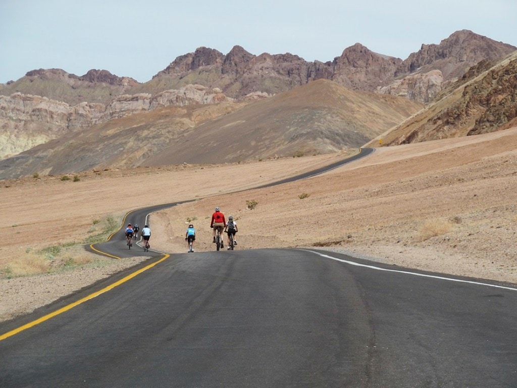 Cyclists pedal down a deserted road in Death Valley.