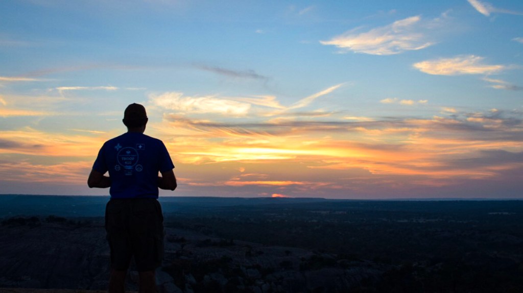 A hiker enjoys the sunset from Enchanted Rock.