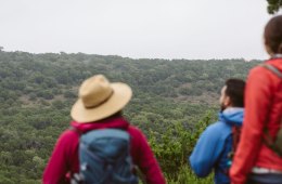 Three hikers look out to the landscape near Austin, Texas