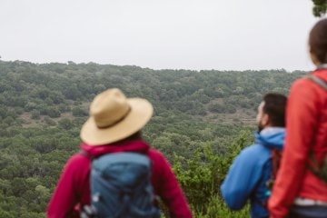 Three hikers look out to the landscape near Austin, Texas