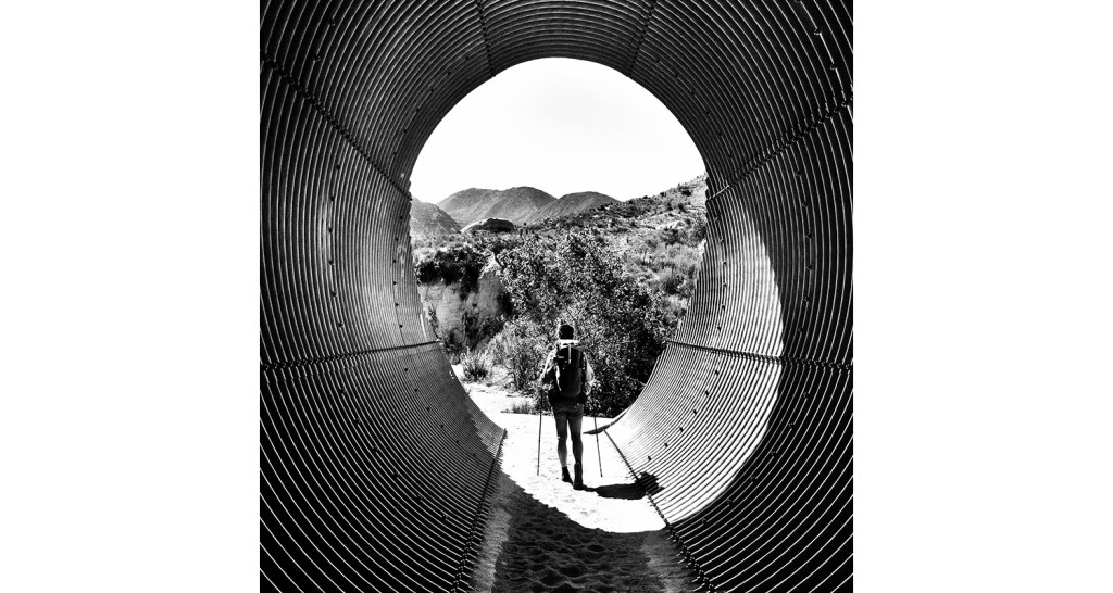 A black-and-white photo of Heather "Anish" Anderson hiking the Pacific Crest Trail in Southern California