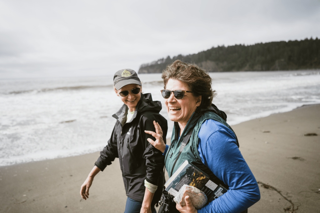 Two hikers laugh, one pushes the other one playfully.