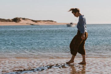 A lone women walks along the beach in Portugal.