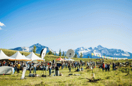 A wide shot of people milling around a film festival with a backdrop of snowcapped peaks