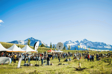 A wide shot of people milling around a film festival with a backdrop of snowcapped peaks