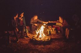Four people around a campfire in a dark night.
