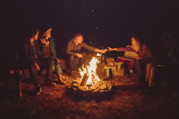Four people around a campfire in a dark night.