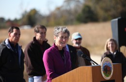 Sally Jewell speaks at a podium, people standing in the background.