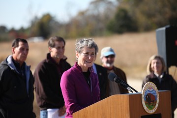 Sally Jewell speaks at a podium, people standing in the background.