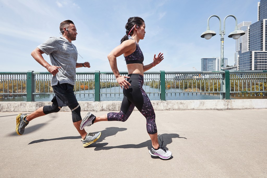 Two runners listen to music using earbuds while they run.