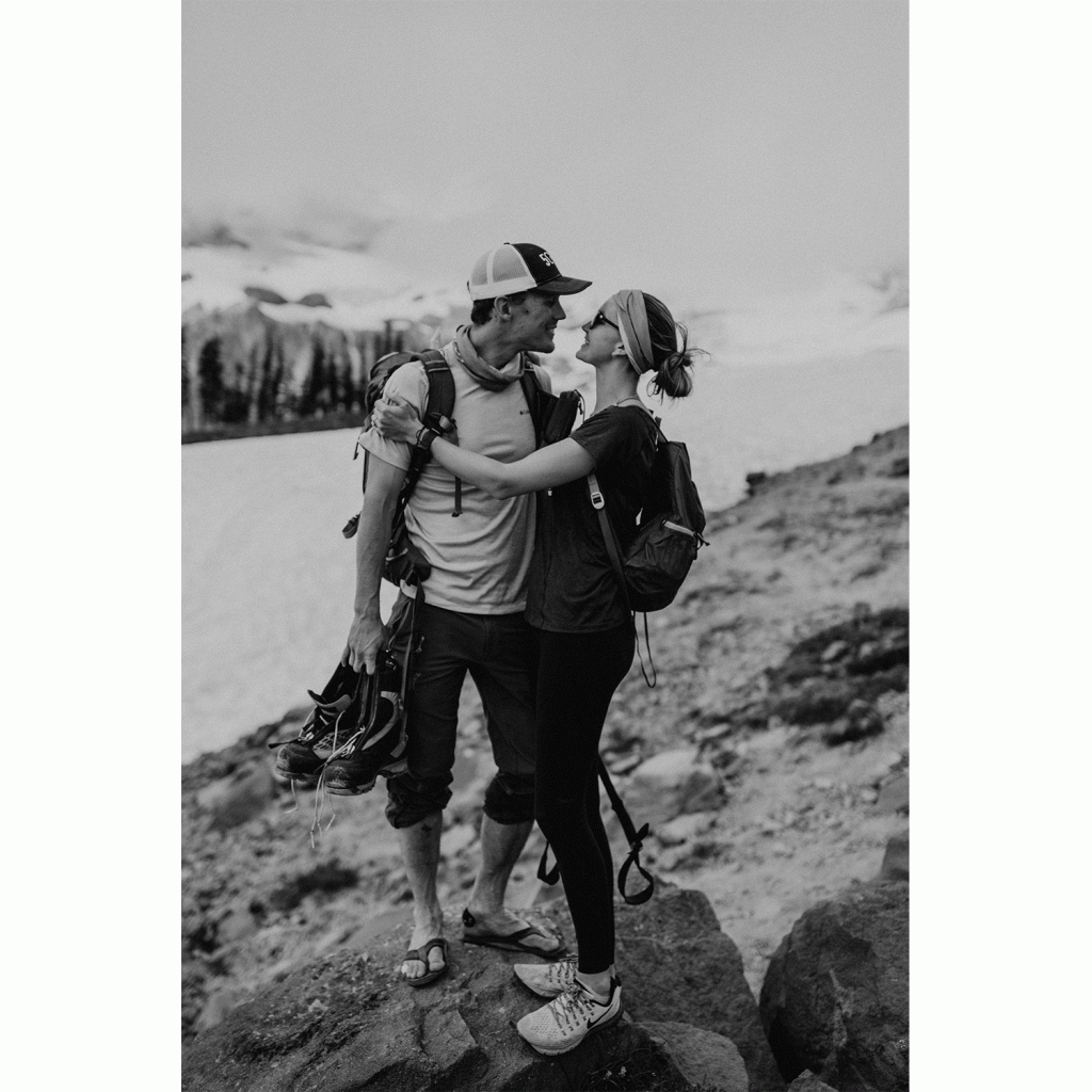 A woman and a man embrace on an exposed rock while wearing workout gear