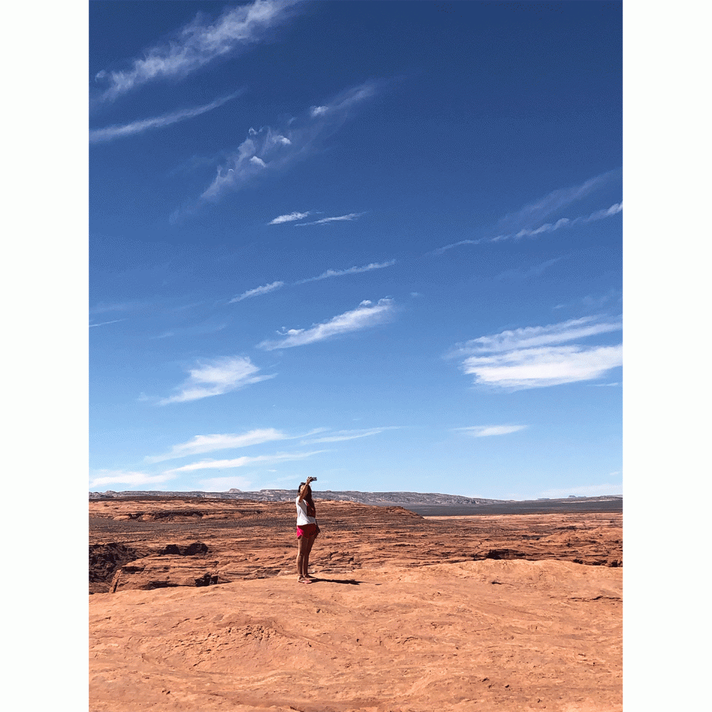 A woman snaps a photo in the desert beneath a vivid blue sky
