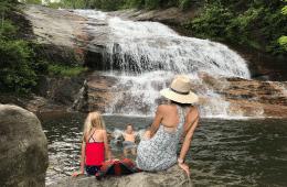 A mom and her kids at a swimming hole with a waterfall in the background