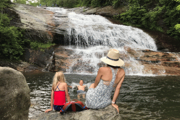 A mom and her kids at a swimming hole with a waterfall in the background
