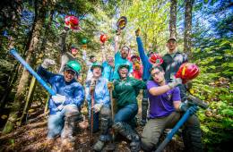 A trail crew celebrates the end of a hard day's work surrounded by leafy green trees