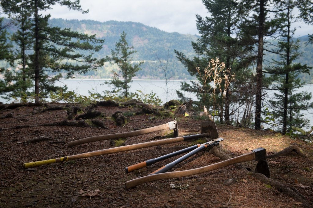 Trail building tools lie on the ground along a trail.
