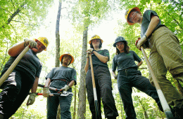 Young women gather around a worksite with shovels in their hands