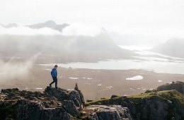 Hiker walks along rock high above a valley.