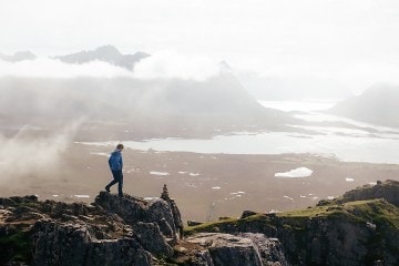 Hiker walks along rock high above a valley.