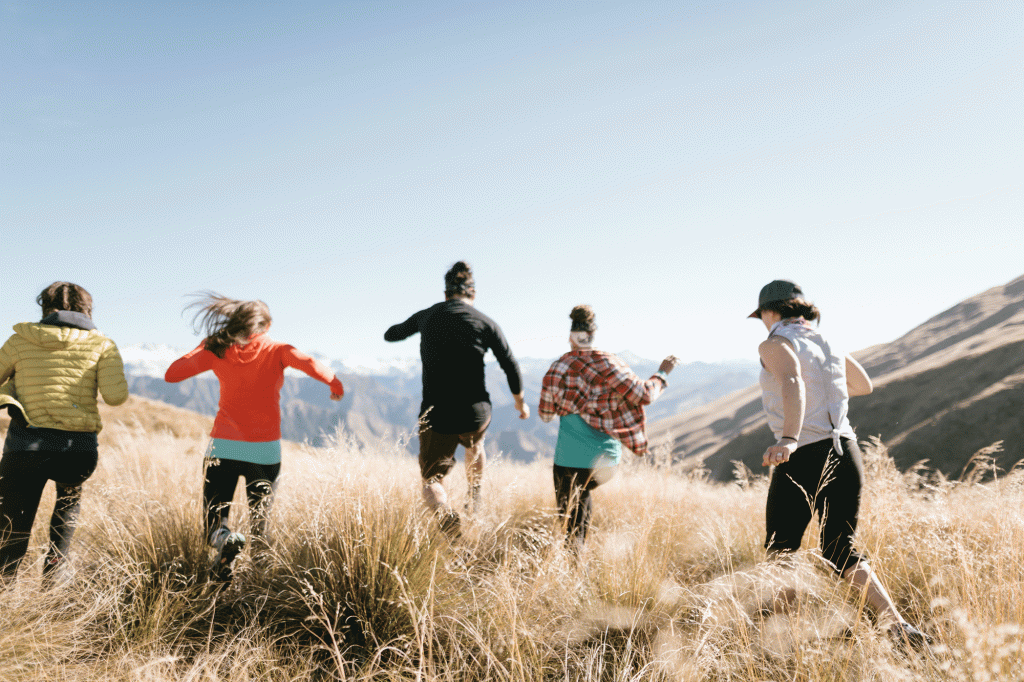 Five friends sprinting into a field of waving gold grass