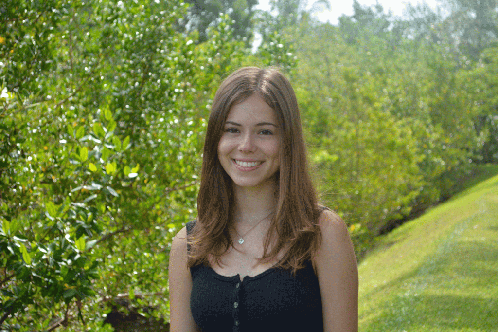 Emma Kavanaugh stands with a green field and green trees behind her