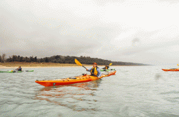 A woman paddles through Lake Michigan with a big smile on her face