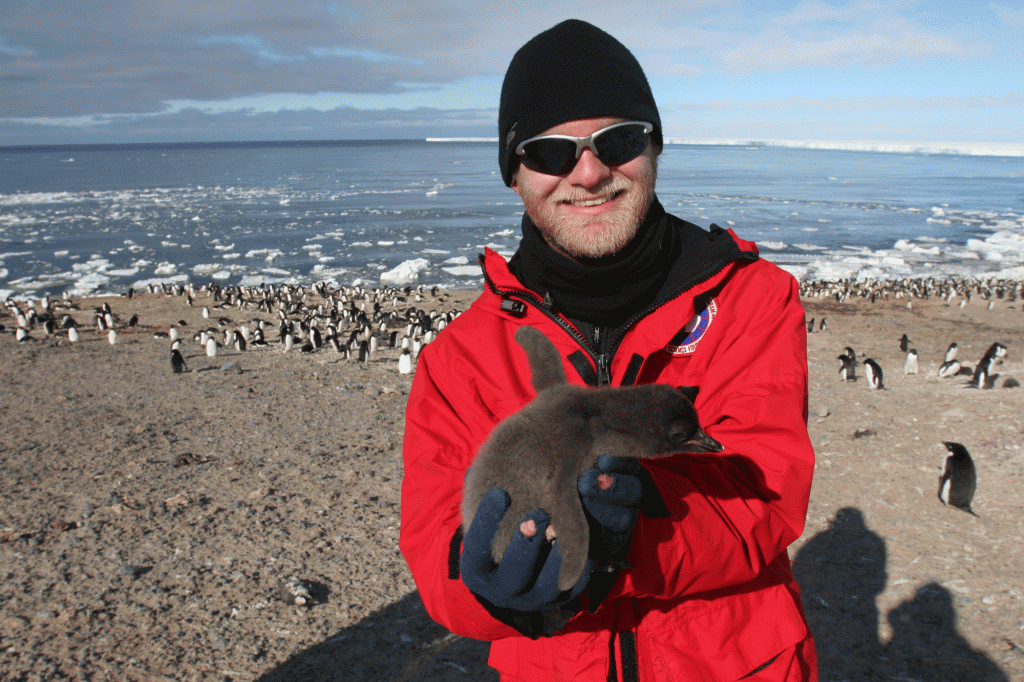 Noah Strycker holds a baby penguin chick in Antarctica