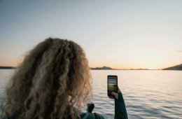 A woman snaps a photo of a beautiful seascape at dusk