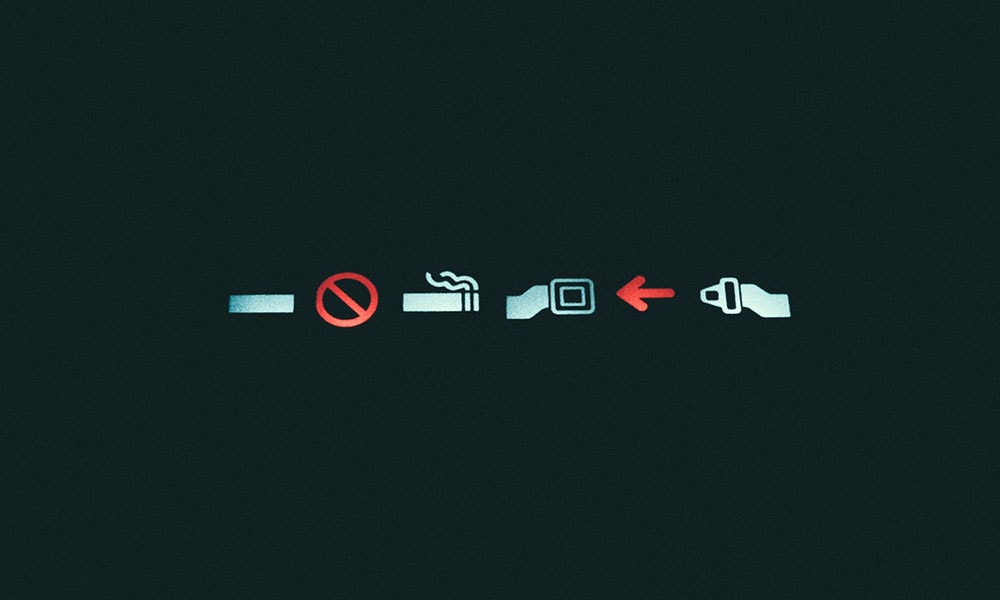 No smoking and seat belt on illuminated signs on an airplane.