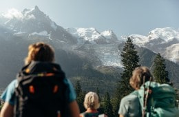 Three people look out on snow-covered peaks in the French Alps.