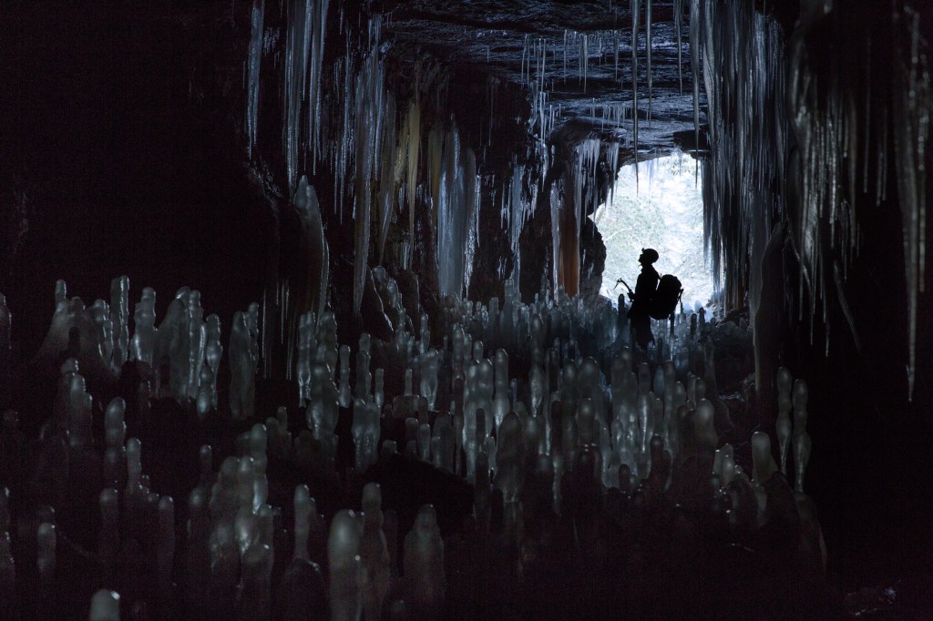 An ice climber inside a dark cave