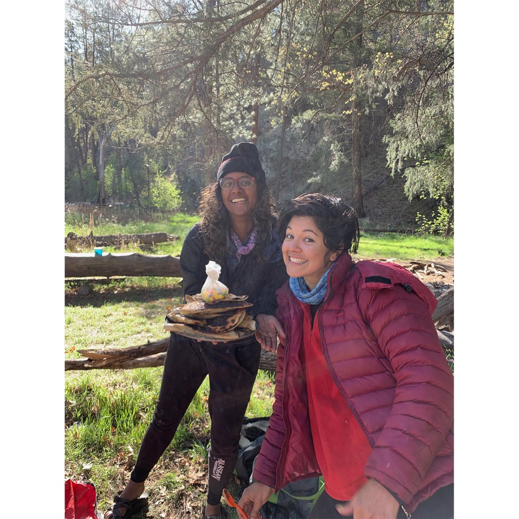Two hikers pose with big smiles and delicious-looking snacks