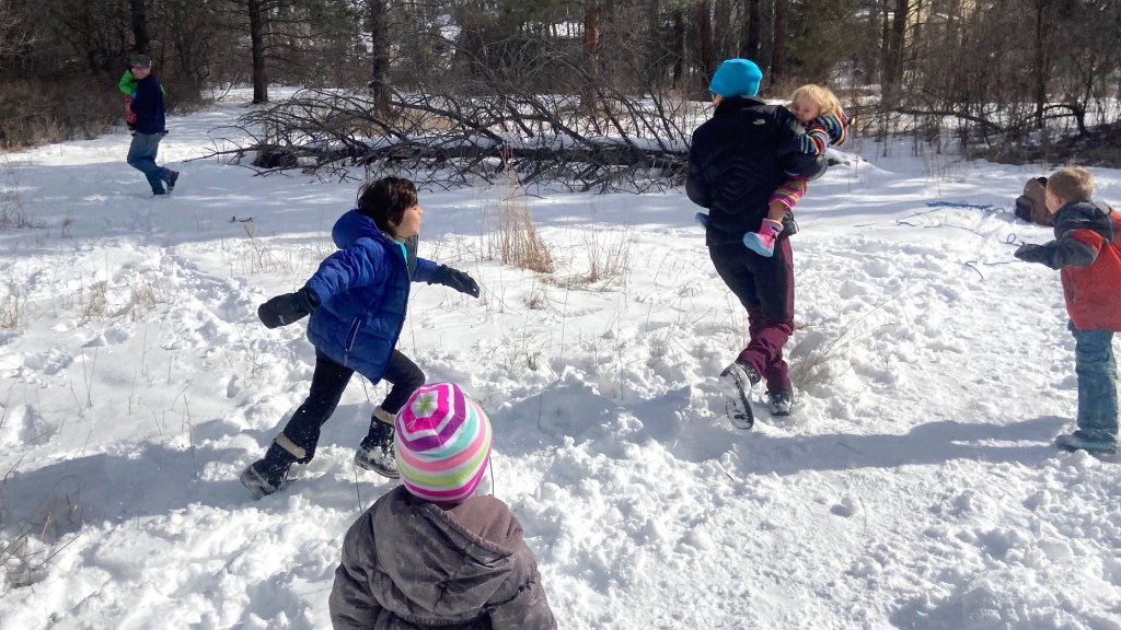 Adults, children and even a toddler join in a rousing game of snowy tag