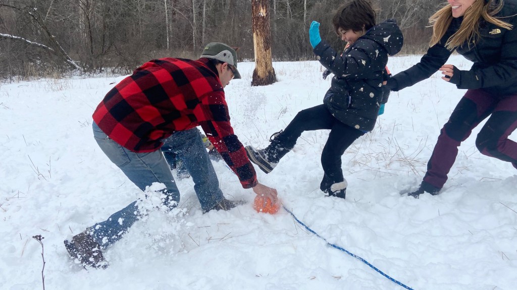 Kids and adults play a rousing game with a ball in white, powdery snow